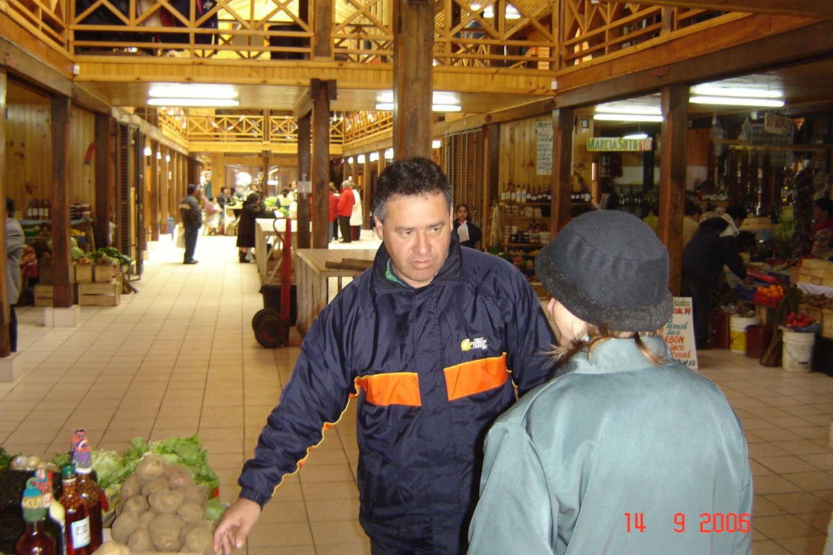 Guia falando sobre as variedades de batatas em visita ao Mercado Municipal de Ancud.